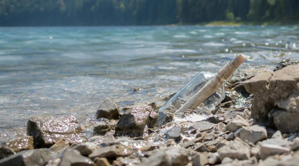 photo of clear glass bottle with rolled paper